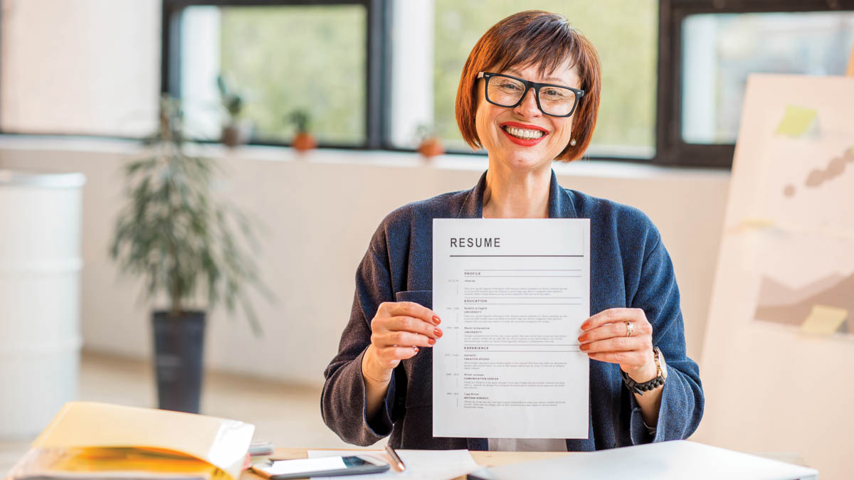 Smiling older woman with glasses showing resume